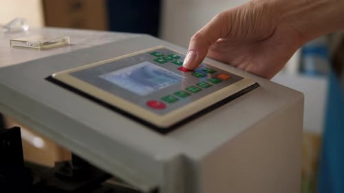 Ein Mann drückt die Knöpfe einer CNC-Maschine zum Schneiden von Holz mit einem Laser