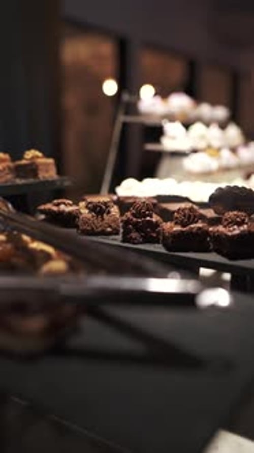 Variety of pastries are displayed on a tiered stand in a bakery, showcasing an assortment of delicio