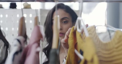 A woman looking at clothes on a railing in a boutique