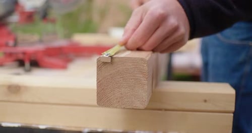 Man Measuring Wooden Plank with Tape Measure