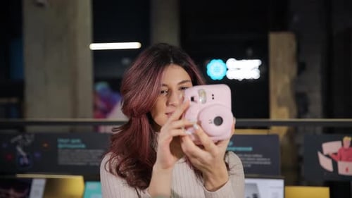 Positive Smiling Girl Chooses Digital Camera in Digital Store