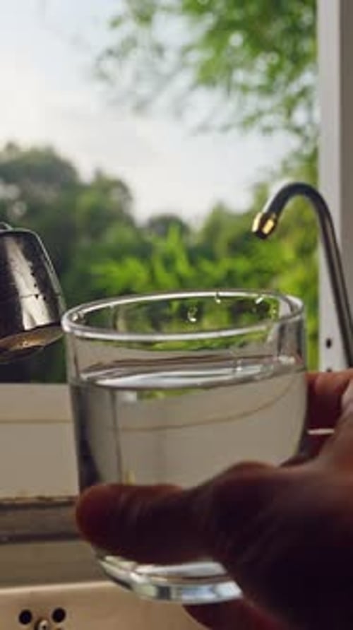 First Person View Of Hand Using Digital Water Quality Tester In Glass Of Fresh Water In Kitchen Near