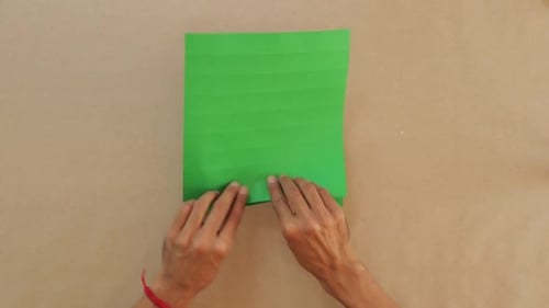 Male Folds Green Paper into Traditional Mexican Fan