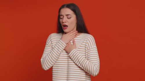 Woman Coughing with Sore Throat Against Orange Background