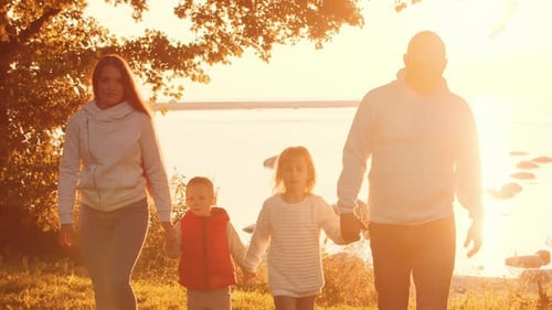 Family Walks Together Near Ocean at Sunset