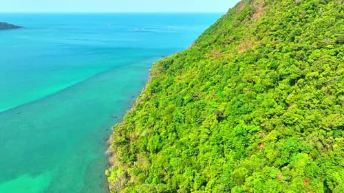Aerial view reveals lush coastal and mountains on tropical island. 4K.