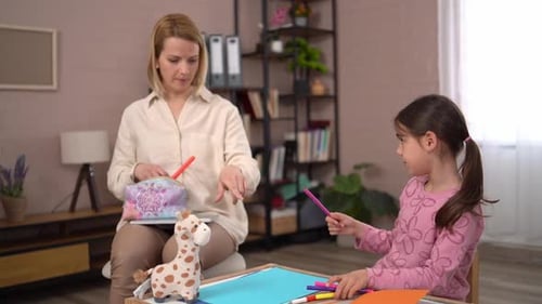 Female psychologist providing art therapy for a young girl in her office during a session