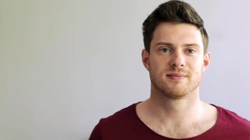 Smiling Man in Red Shirt Against Grey Background