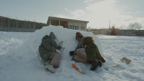 Young Adults Building Snow Fort on Sunny Winter Day
