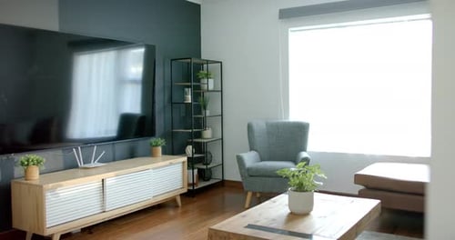 Die Kamera wird geschwenkt, um den linken Rand freizulegen. Die Wand, der Fernseher und die Konsole werden angezeigt, während sich die Reflexionen ändern