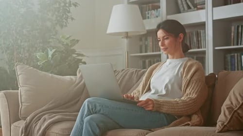 Woman Using Laptop Relaxing on Couch at Home
