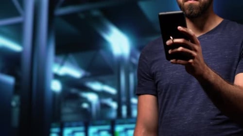 Adult Holding Phone in Dark Data Center