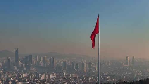 Red Flag Waving Over Distant Cityscape