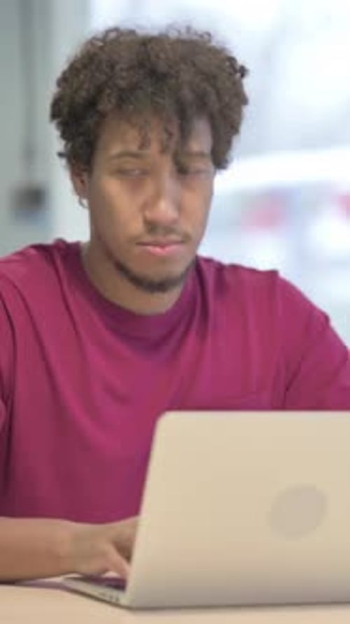 Young Adult Man Uses Laptop Indoors