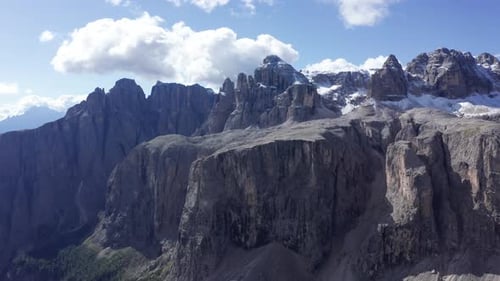 Aerial drone shot flying over beautiful mountain ridge of Dolomites with snowcapped view at the back