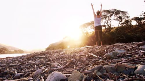 Woman Practicing Yoga on Rocky Beach at Sunrise