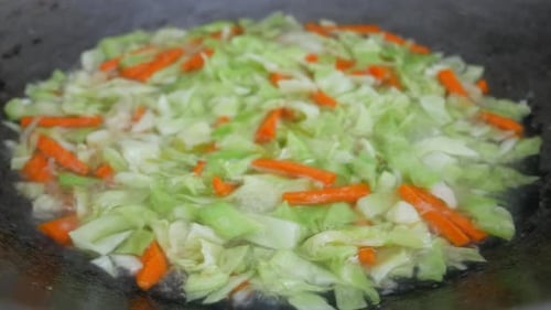 Fresh green cabbage is fried in a pan using hot cooking oil. Mix with carrot and chilli. Traditional