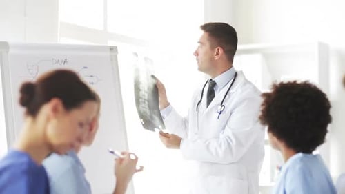 Happy doctors meeting at hospital showing x-ray of human spine to interns