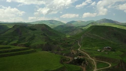 Scenic View of a Mountain Range with a Road Going Through It and a Few Buildings on the Side