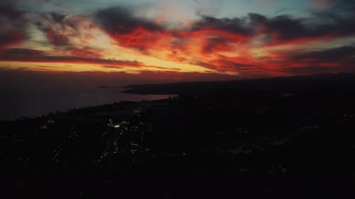 Aerial Of Dramatic Orange Red Sunset Through The Cloud With Silhouette Of Coastline Below