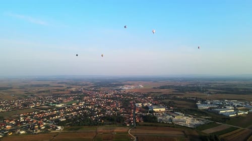 Stunning 4K aerial footage of a drone filming hot air balloons. Flying over farming fields and river