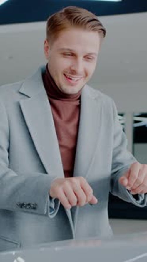 Joyful Man Touches Car Bonnet Putting Down Head in Dealership