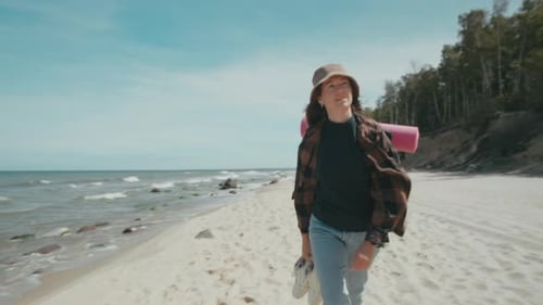 Female tourist with touring backpack walking on seashore