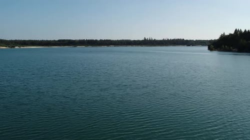 Peaceful crystal blue lake during the day. Drone shot flying over the water in 4K.