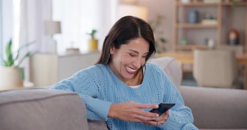 Woman Using Smartphone and Smiling on Couch at Home