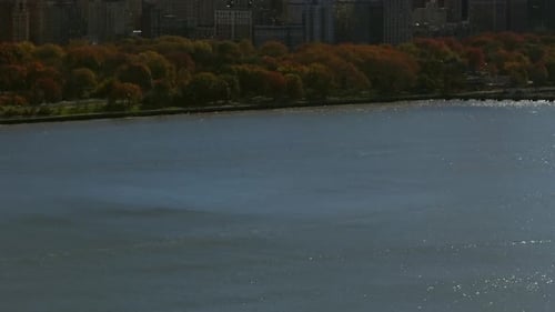 An aerial view over the Hudson River on a sunny day in New York City. The drone camera tilted down o