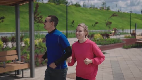 A Man and a Woman Run Around a Beautiful and Wellmaintained City Park Summer Cardio Training is