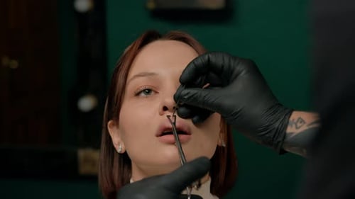Piercing studio interior - piercing master makes a piercing to a girl, lip piercing