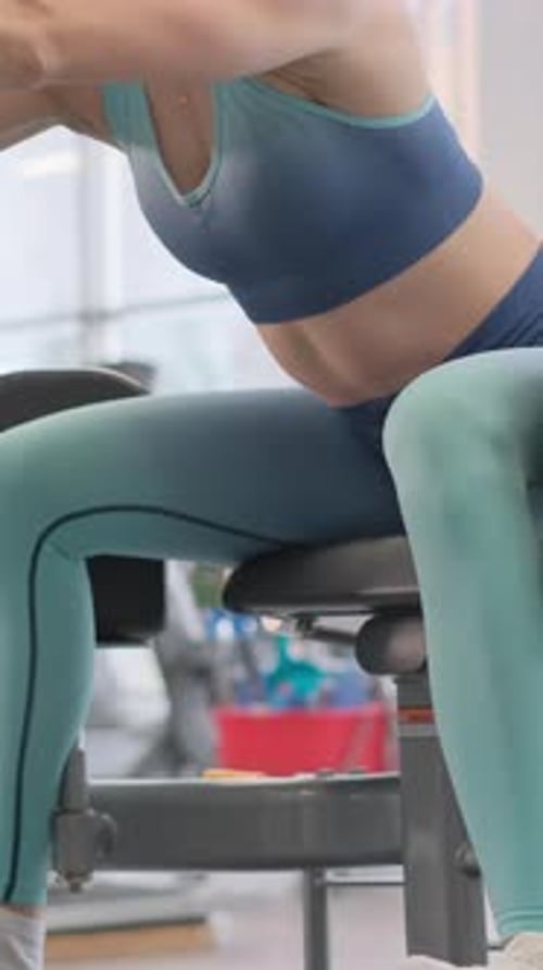 A Woman is Exercising on a Squat Machine at the Gym