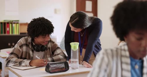 University, students and help from professor in classroom for exam in education