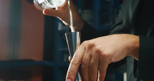 Close up of a professional bartender is preparing an alcoholic cocktail with ice cubes to customer