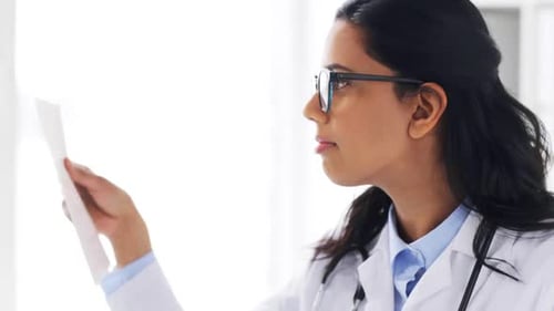 Young indian female doctor examines medical reports at a hospital