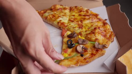Hand taking a slice of vegetarian pizza from box. Close up
