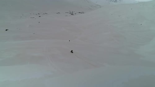 Snowmobile Riding Across Snowy Mountains Aerial View