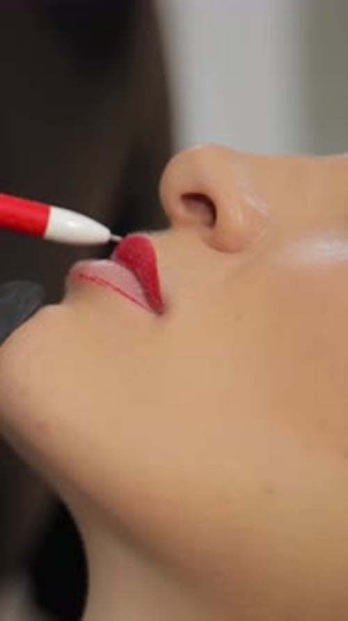 A Closeup View Shows the Precise Application of Bright Red Lip Pencil to a Woman's Lips During Lip