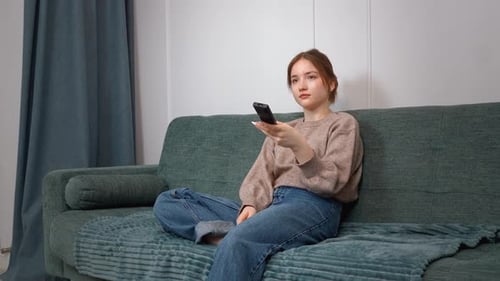 Teenage Girl Relaxing on Couch with Remote Control