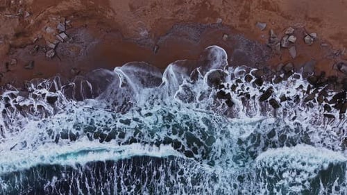 Waves crash on rocky shore during sunset near coastal area
