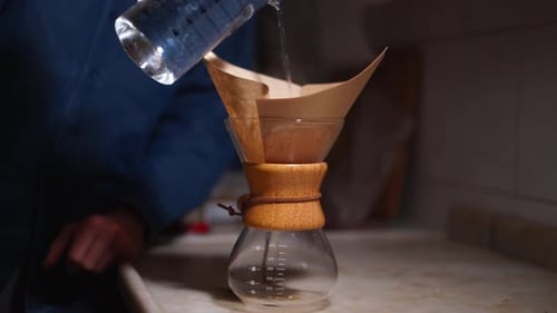 Pouring Water Into a Glass Coffee Maker