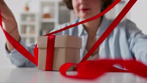 Close-up female hands open a gift. Opening a gift box by female hands, Festive atmosphere intriguing
