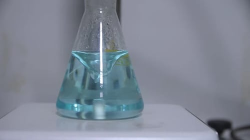 Mixing Light Blue Liquid in Erlenmeyer Flask in Lab Closeup