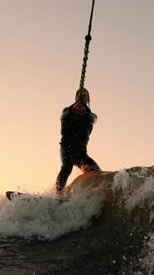 Dynamic Water Sport Action Surfer Masterfully Riding Waves at Sunset with a Tow Rope Capturing the