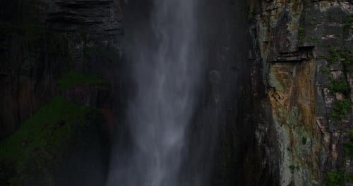 Powerful Hidden Waterfall Cascading Down Ancient Dark Jagged Rock Cliffs