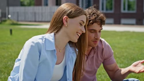 Pair Greeting Online Meeting By Laptop Sitting Together at Green Lawn Closeup