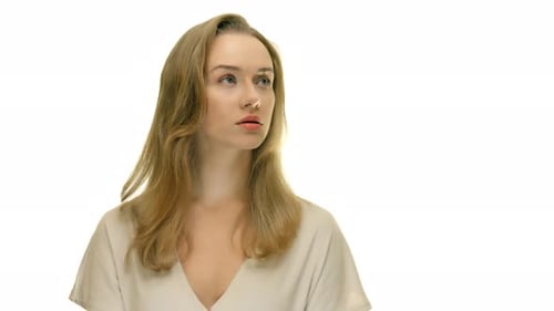 A close-up of a woman looking off into the distance, then turning her head to face the camera, on a