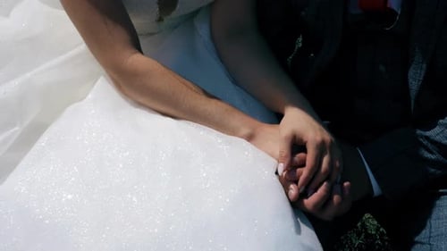 Casal recém-casado de mãos dadas em uma cerimônia de casamento ao ar livre iluminada pelo sol