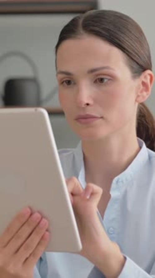 Focused Woman Uses Tablet Device at Home Indoors